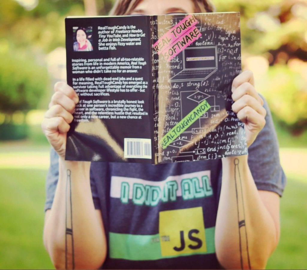 girl with I Did it All for the JS JavaScript shirt holding up Real Tough Software book