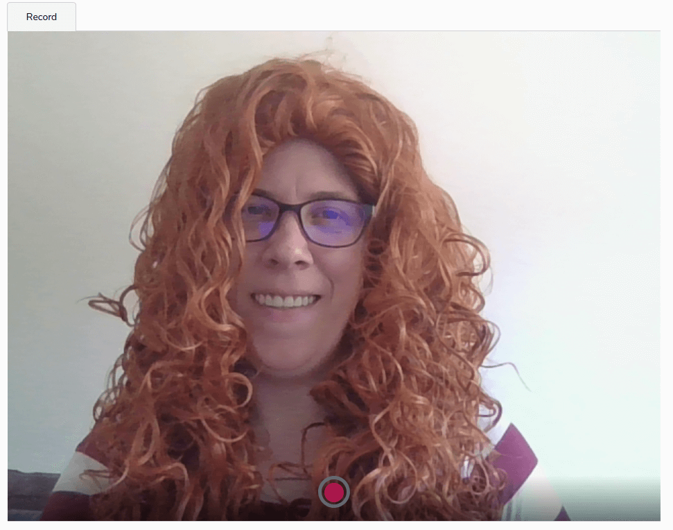 woman with red curly hair smiling while being recorded for behavioral interview