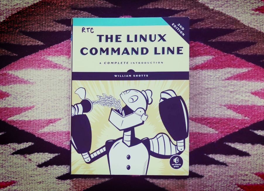 The Linux Command Line book on top of rug with pink, black, white and brown triangles